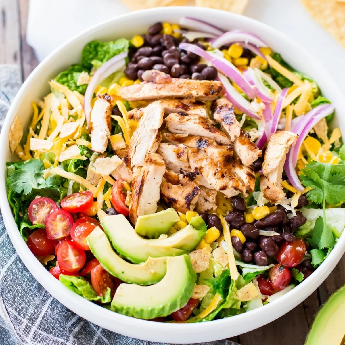 Freshly grilled honey lime chicken slices rest atop a bed of crisp romaine lettuce with black beans, corn, and diced avocado.  