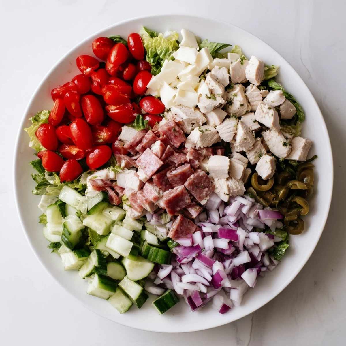 A vibrant bowl of Italian Deli Chopped Chicken Salad with crisp romaine, juicy tomatoes, and a tangy herb dressing.