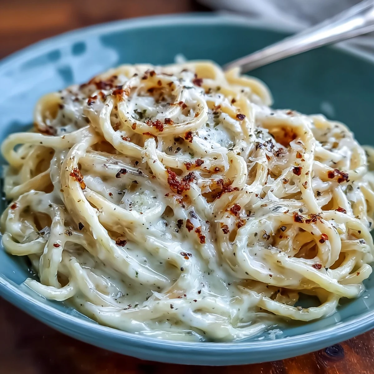 Steaming spaghetti tossed in a skillet with freshly cracked black pepper and Pecorino Romano to create Cacio e Pepe.