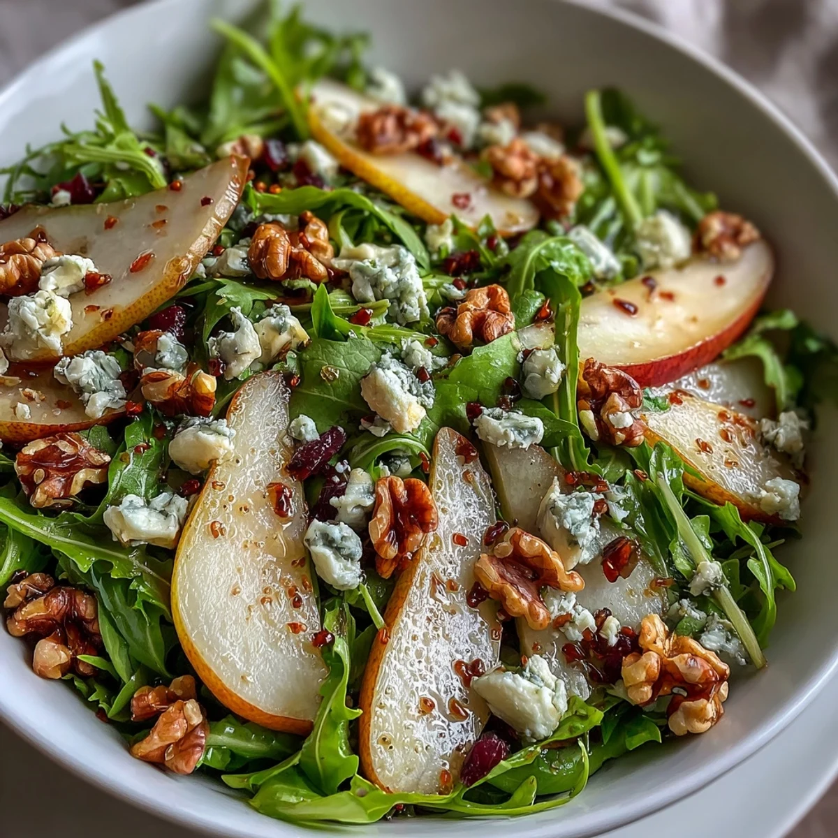 Fresh arugula and sliced ripe pears topped with crumbled blue cheese and toasted walnuts in an Arugula and Pear Bowl.