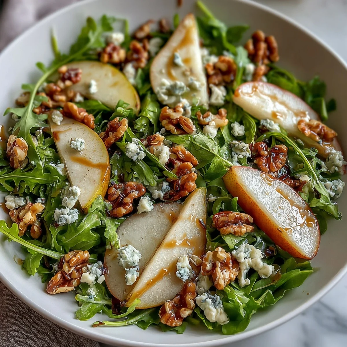 Arugula and Pear Bowl served on a white plate with balsamic dressing drizzled over the vibrant salad.
