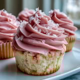 Moist Pink Velvet Cupcakes topped with fluffy swirls of Vanilla Buttercream Frosting on a white marble countertop.