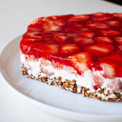 Vibrant red strawberry pieces suspended in Jell-O atop a decadent Strawberry Pretzel Salad.