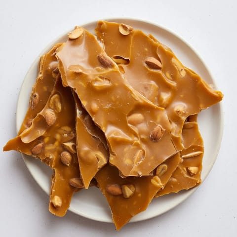 Close-up of freshly broken Peanut Brittle showcases the crunchy texture and roasted peanuts.
