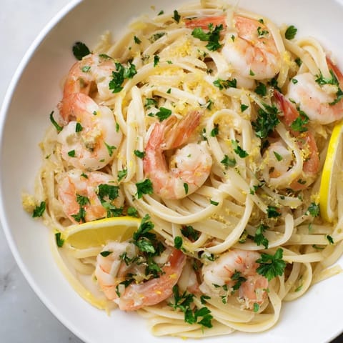 Succulent shrimp in garlic butter sauce tossed with al dente linguine, garnished with fresh parsley and lemon zest.