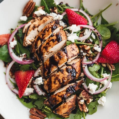A vibrant bowl of Honey Balsamic Chicken Salad features juicy grilled chicken, sweet strawberries, and creamy goat cheese on fresh greens.