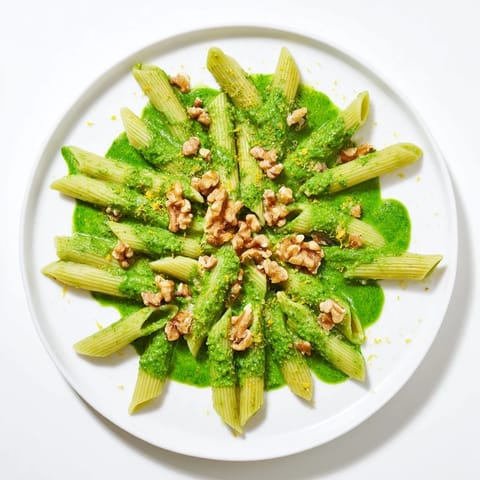 Overhead view of vegan Creamy Spinach Walnut Pasta, showcasing the velvety texture and garnish of chopped walnuts and lemon zest.