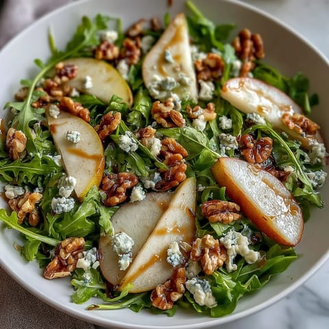 Arugula and Pear Bowl served on a white plate with balsamic dressing drizzled over the vibrant salad.