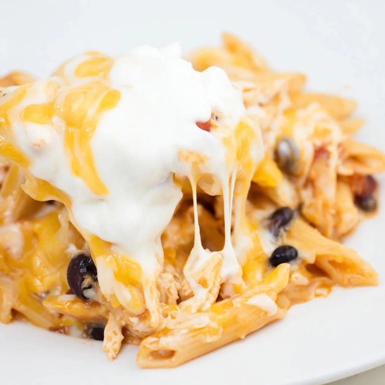 Fresh diced avocado and green onions garnish a warm bowl of Chicken Enchilada Pasta, ready for a weeknight dinner.